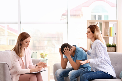 teenage boy and his mother talking to the therapist